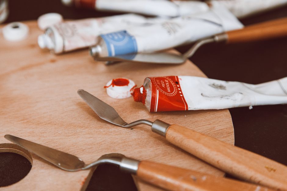 Close-up of a painter's tools including paint tubes and palette knives, perfect for artistic creativity themes.
